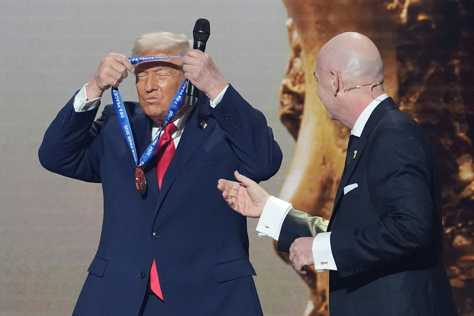Donald Trump tek på seg vinnarmedaljen for den første fredsprisen frå Fifa, overlevert av Fifa-president Gianni Infantino under VM-trekninga 5. desember 2025. Foto: AP Photo / Evan Vucci, File 