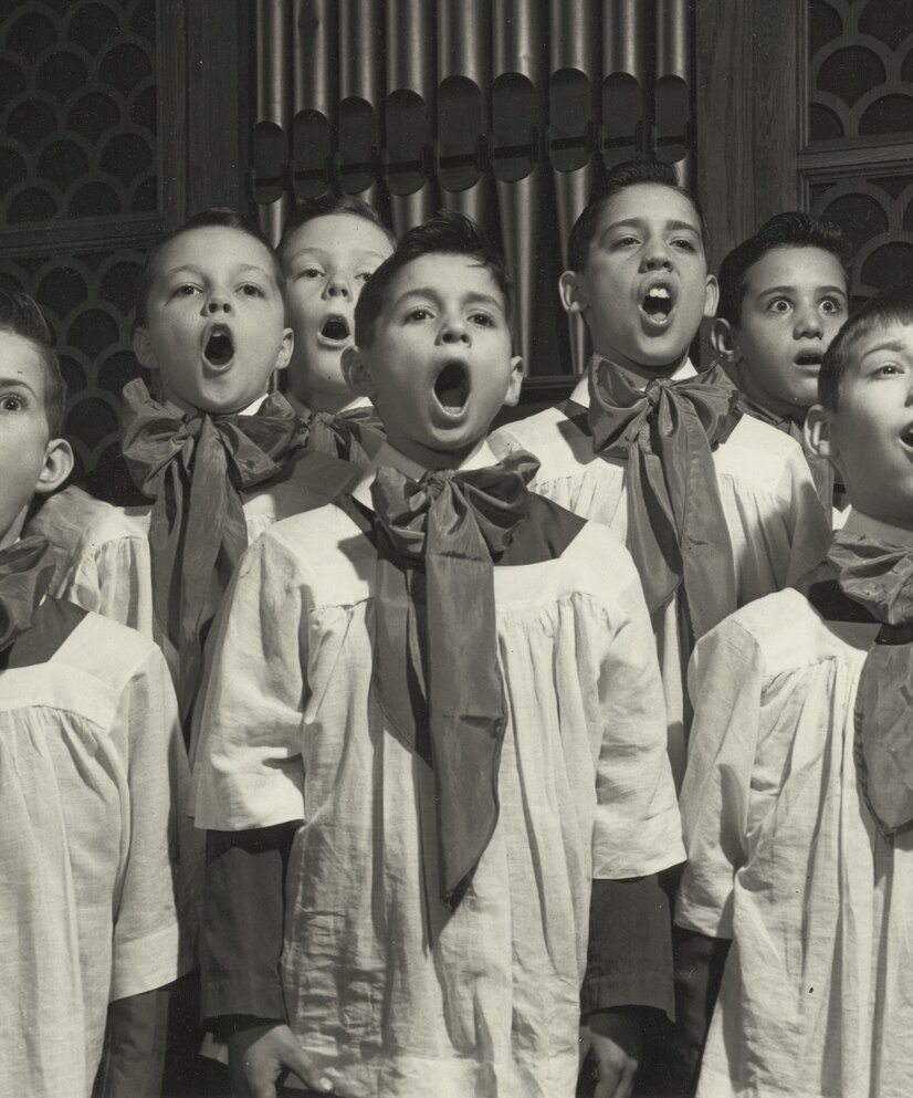 Svart-hvitt illustrasjonsfoto av korgutter med kapper og store sløyfer rundt halsen. 